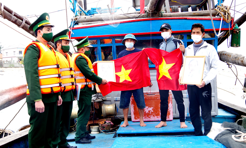  Cán bộ, chiến sĩ Đồn BPCK Cảng Gianh tặng cờ Tổ quốc, ảnh Bác Hồ và phát tờ rơi tuyên truyền pháp luật, phòng, chống dịch Covid-19 cho ngư dân. 