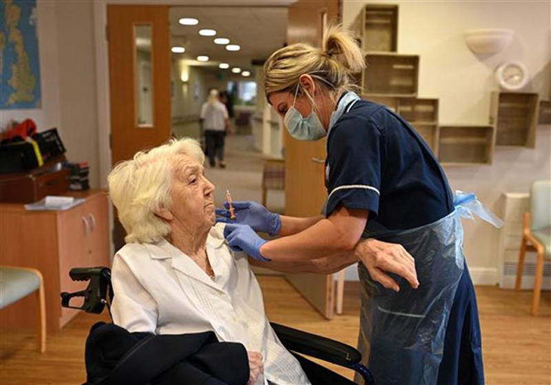 Nhân viên y tế tiêm vaccine phòng COVID-19 cho một cụ bà ở Wigan (Anh). (Ảnh: AFP/TTXVN)