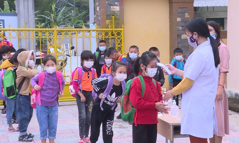 Thực hiện đo thân nhiệt cho các em học sinh khi đến trường.