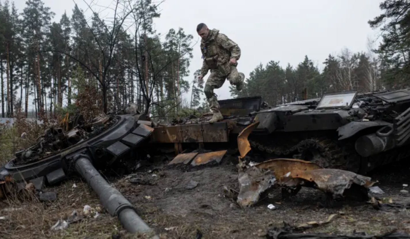 Binh sĩ Ukraine vượt qua một xác xe tăng ở Dmytrivka, ngoại ô Kiev ngày 2/4/2022. Ảnh: Getty Images