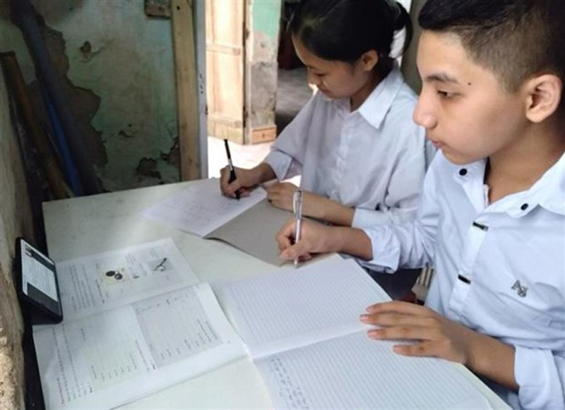 Nhiều gia đình khó khăn trong việc mua máy tính trong khi học sinh học trực tuyến trên điện thoại dễ bị ảnh hưởng thị lực. Không ít trường hợp hai học sinh phải học chung trên một thiết bị. (Ảnh: TTXVN phát)