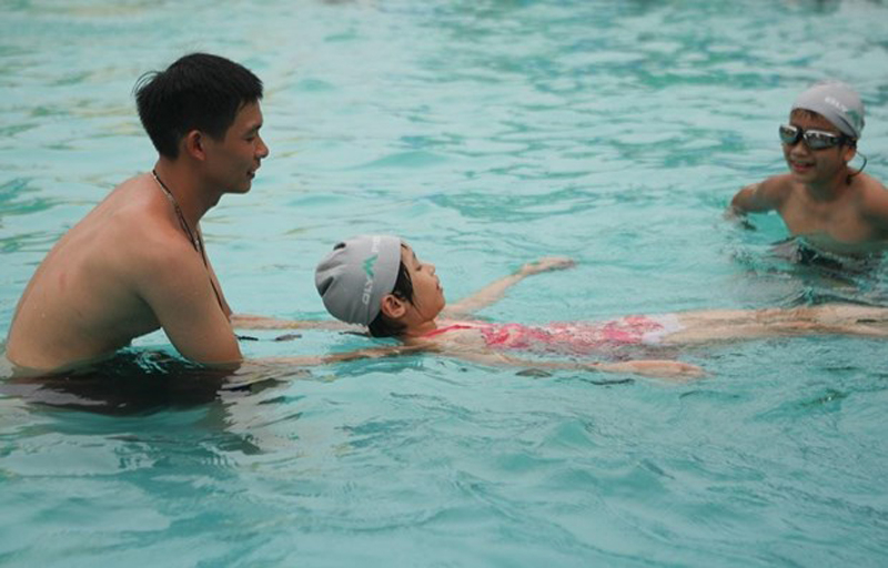 Huấn luyện viên hướng dẫn học sinh kỹ năng cơ bản để học bơi. (Ảnh: Thanh Tùng/TTXVN)