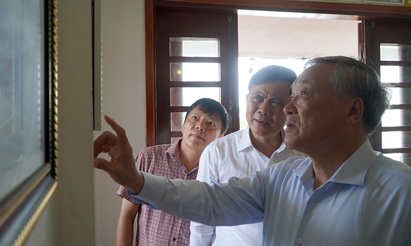 Đồng chí Nguyễn Hòa Bình và đồng chí Trần Thắng ngắm những bức ảnh và kỷ vật lưu niệm tại gia đình Mẹ Suốt
