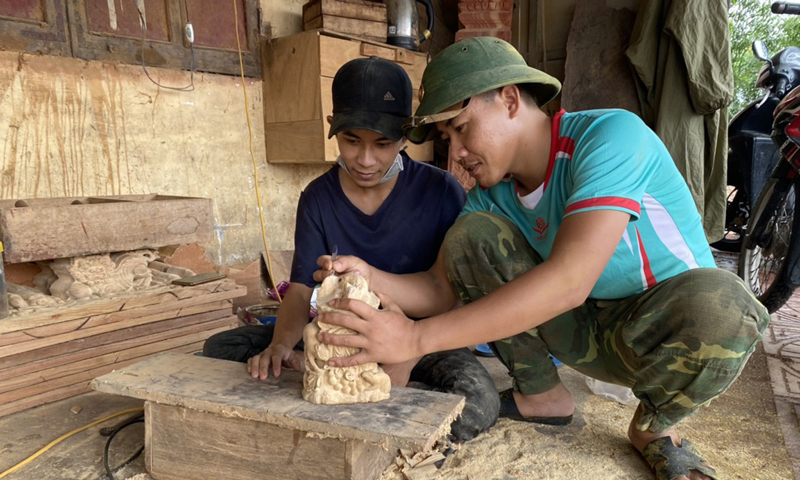 Nguyễn Thế Sơn hướng dẫn chạm khắc gỗ cho một đoàn viên trẻ.