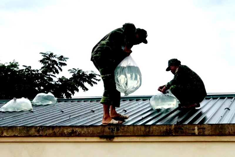 Cán bộ, chiến sĩ đồn Biên phòng Ra Mai, BĐBP tỉnh giúp nhân dân chằng chống nhà phòng, chống bão.