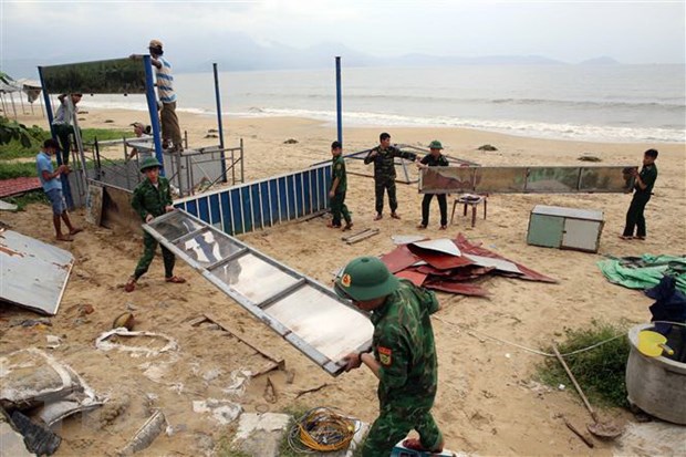 Cán bộ, chiến sỹ biên phòng đồn Phú Lộc, quận Thanh Khê, thành phố Đà Nẵng giúp dân tháo gỡ, di dời tài sản trên bãi biển vào sâu đất liền tránh bão số 4. (Ảnh: Trần Lê Lâm/TTXVN)