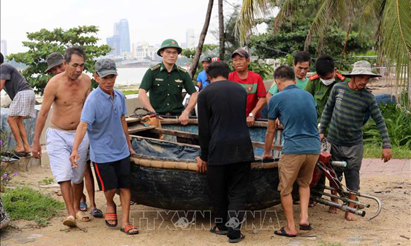 Cán bộ, chiến sĩ biên phòng đồn Phú Lộc, quận Thanh Khê (Đà Nẵng) giúp dân tháo gỡ di dời tài sản trên bãi biển vào sâu đất liền tránh bão Noru. Ảnh: Trần Lê Tâm/TTXVN.