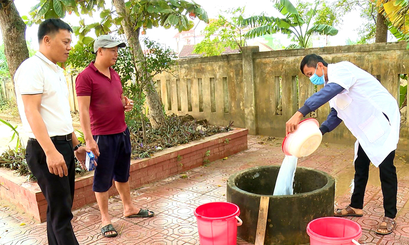 Cán bộ y tế hướng dẫn người dân cách khử khuẩn nguồn nước sau lũ lụt.