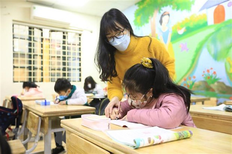 Cô giáo Nghiêm Thị Như Ý hướng dẫn học sinh lớp 2G - Trường tiểu học Phạm Tu (Thanh Trì) tập viết. (Ảnh: Hoàng Hiếu/TTXVN)