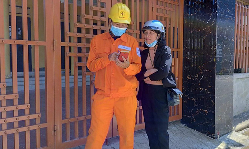 Nhân viên Điện lực Quảng Trạch hướng dẫn khách hàng cài đặt App trên thiết bị di động để theo dõi sản lượng hàng ngày.