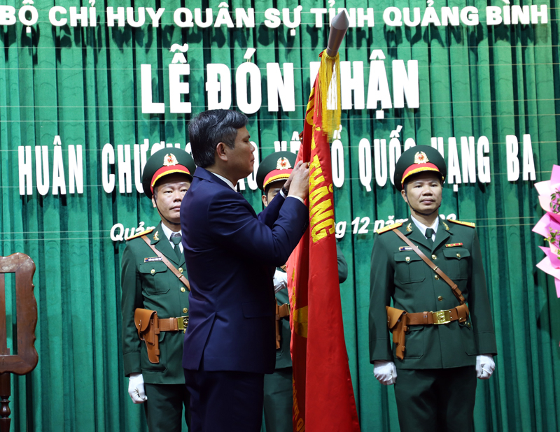 Đồng chí Trần Thắng, Phó Bí thư Tỉnh ủy, Chủ tịch UBND tỉnh gắn Huân chương BVTQ hạng Ba lên cờ Quyết Thắng của LLVT tỉnh