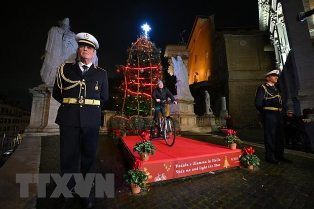 Người dân đạp xe để cung cấp năng lượng thắp sáng cây thông Noel bên ngoài Tòa thị chính Rome ở Quảng trường đồi Capitolinus , ngày 13/12. (Ảnh: AFP/TTXVN)