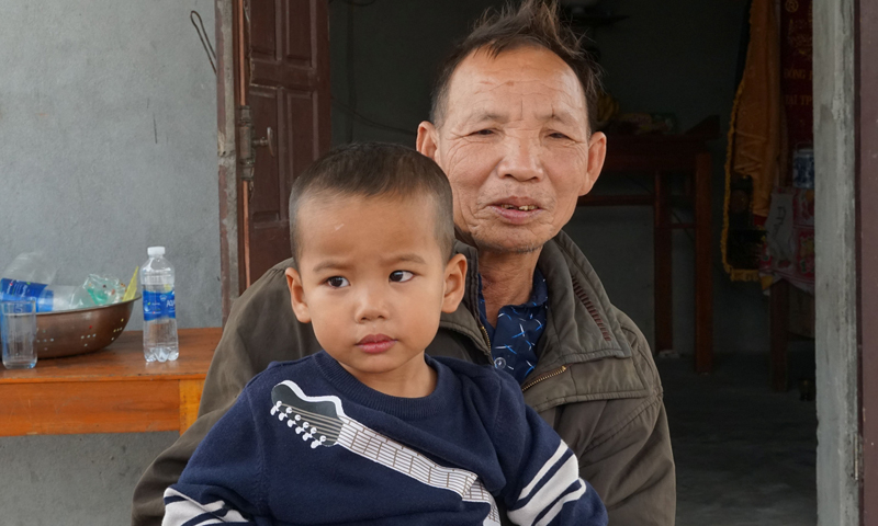 Bé Bùi Ánh Dương và ông Bùi Văn Kỳ, người đang cưu mang bé Dương.