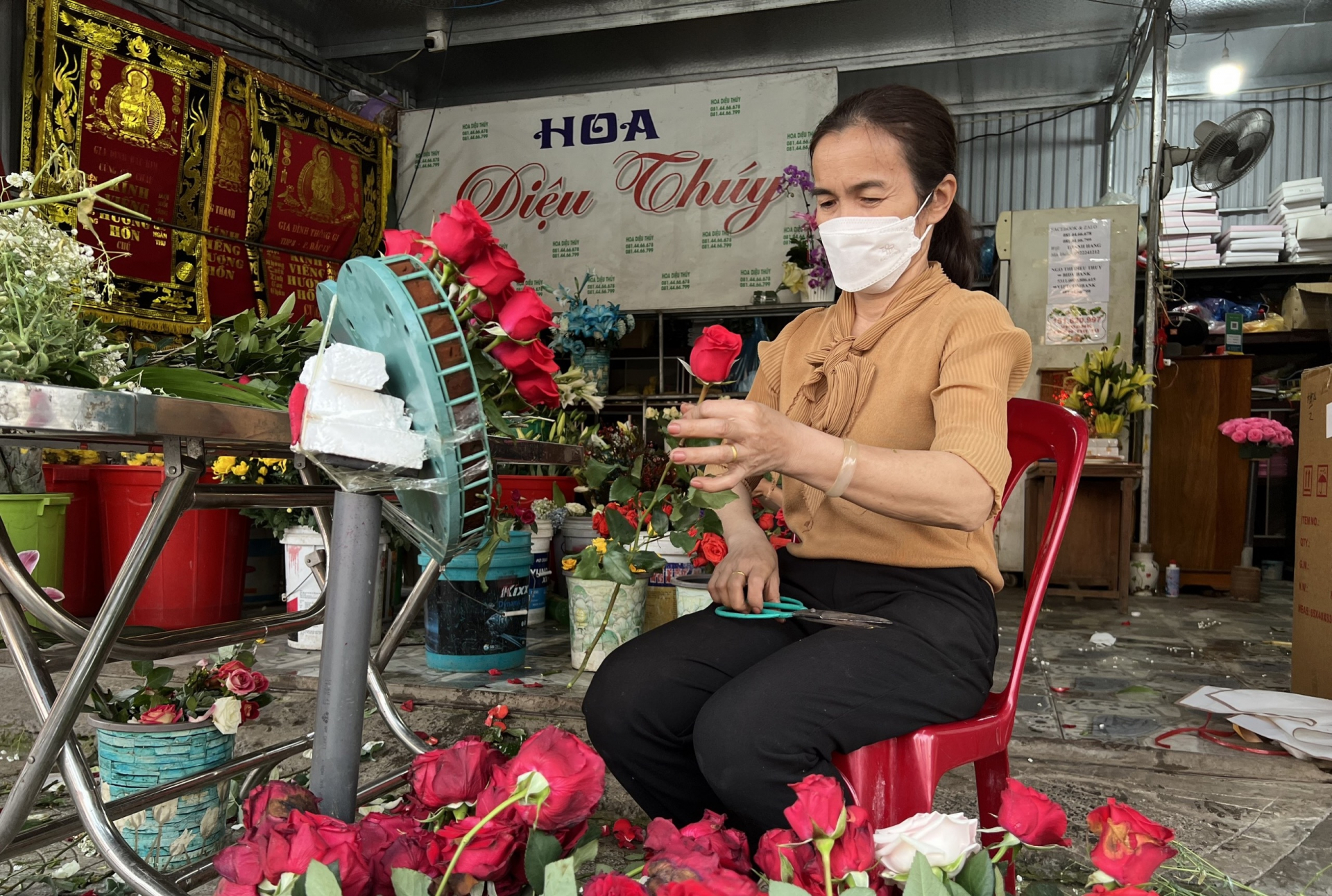 Chị Trần Thị Tú, chủ của hàng hoa tươi ở đường Phạm Văn Đồng (TP. Đồng Hới) chuẩn bị hoa tươi cho khách. Theo chị, thị trường hoa tươi năm nay mua sẵn có trầm hơn so với mọi năm do phong trào các bạn trẻ lựa chọn làm hoa sáp 