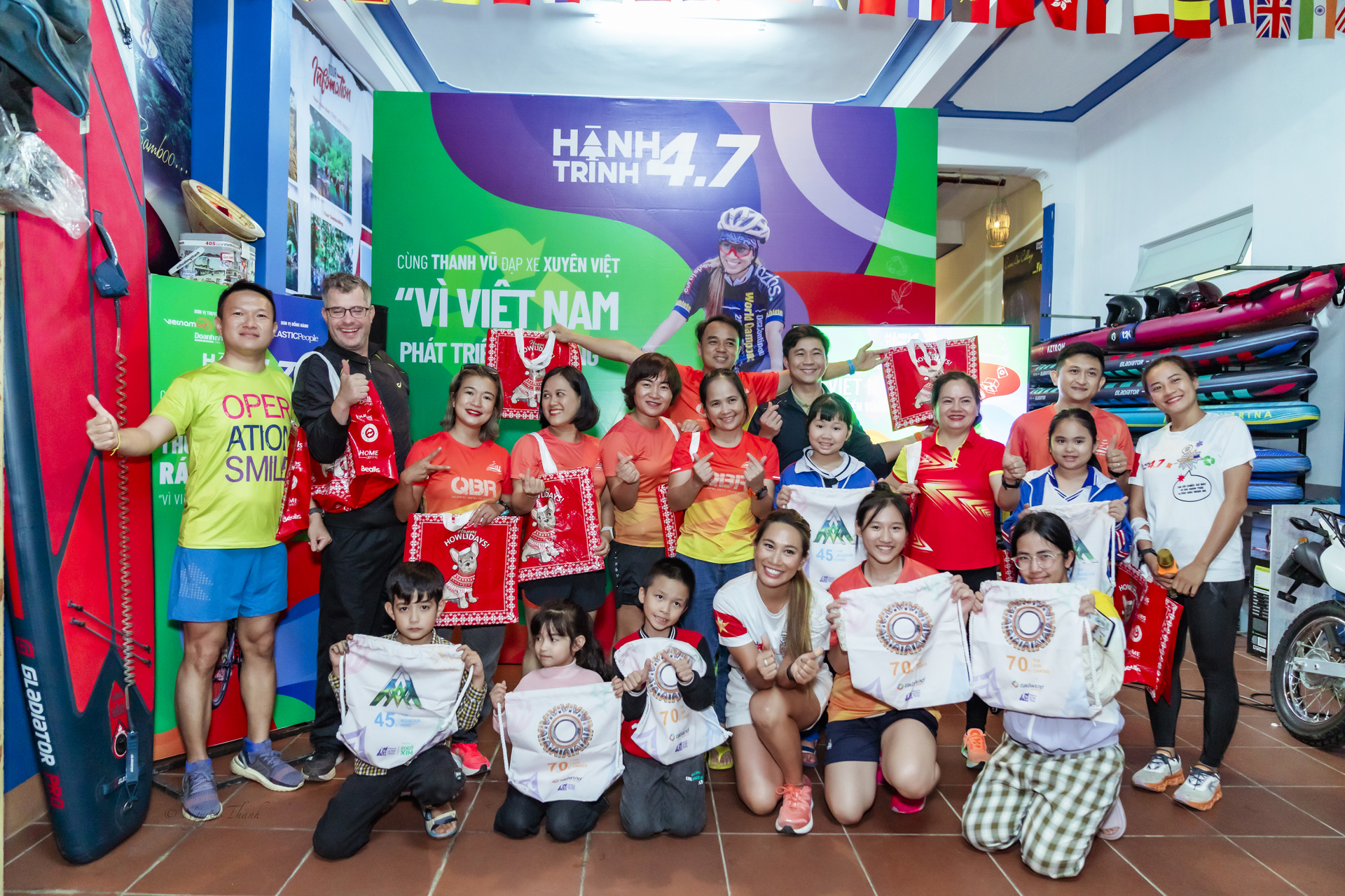 Thanh Vũ (hàng ngồi) trao tặng túi đi chợ có thể dùng nhiều lần nhằm hạn chế dần túi nilon thải ra môi trường.