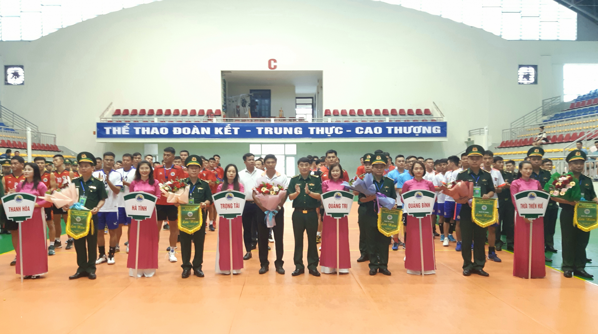 Đại tá Hồ Thanh Sơn Phó Chỉ huy trưởng, Tham mưu trưởng BĐBP tỉnh (ở giữa) tặng hoa và cờ lưu niệm cho các đội tham dự khai mạc Hội thao bóng chuyền Bảng C khu vực I.