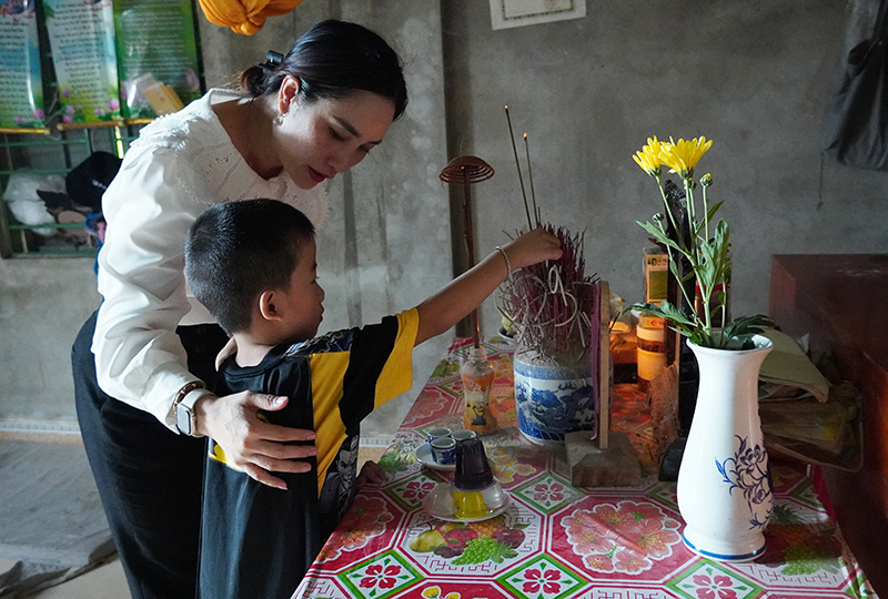 Hoàng Phi Long cùng mẹ Lan thắp hương cho mẹ đẻ, cháu còn quá nhỏ để cảm nhận được sự mất mát lớn lao.