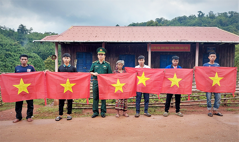 Cán bộ Đồn Biên phòng Cà Roòng tặng cờ Tổ quốc cho nhân dân xã Thượng Trạch (Bố Trạch).