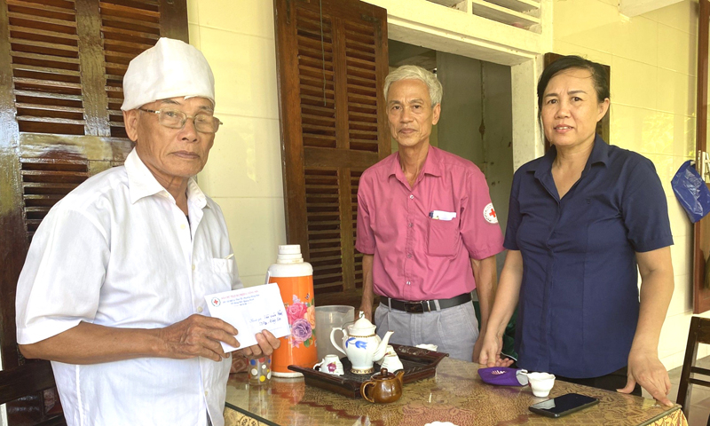 Ông Ngô Hạnh Phúc (ở giữa), Chủ tịch Hội Chữ thập đỏ phường Đồng Sơn (TP. Đồng Hới) trao quà “địa chỉ nhân đạo” cho hộ nghèo trên địa bàn.