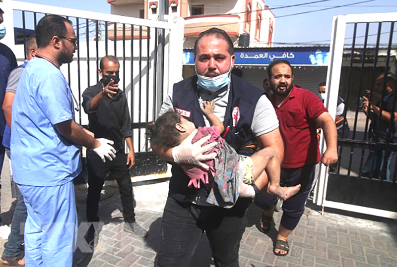 Người đàn ông ôm một em nhỏ bị thương sau cuộc không kích của Israel xuống Dải Gaza ngày 23/10/2023. (Ảnh: THX/TTXVN)