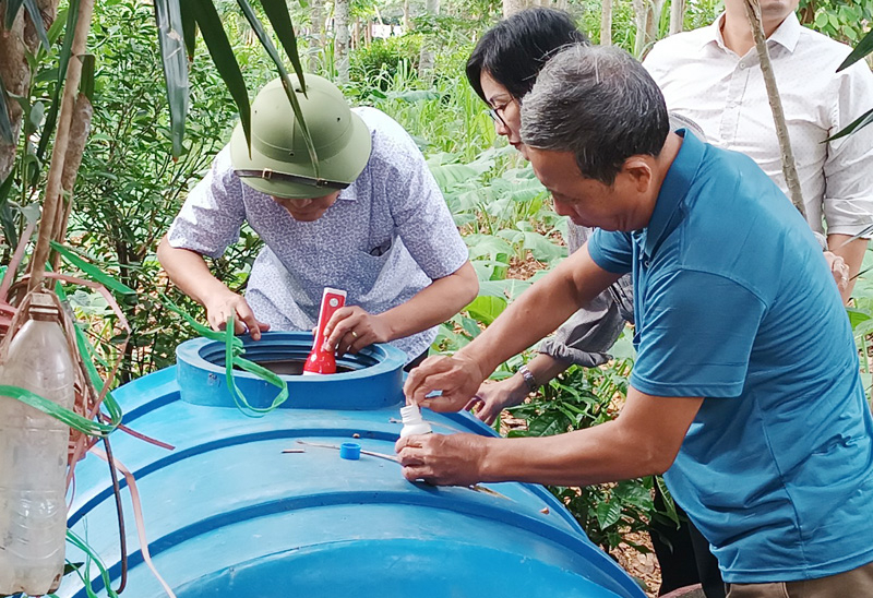 Cán bộ Trung tâm Y tế Bố Trạch hướng dẫn người dân Lý Trạch sử dụng hóa chất diệt loăng quăng/bọ gậy.