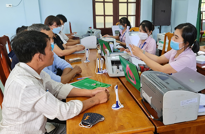Nhân viên ngân hàng hỗ trợ khách hàng các gói vay chính sách xã hội.
