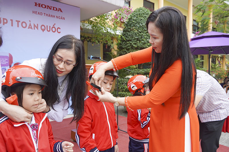 Giáo viên Trường Tiểu học Đồng Mỹ đội mũ bảo hiểm cho học sinh