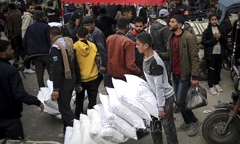 Người dân Palestine nhận lương thực viện trợ tại trung tâm phân phối của Cơ quan cứu trợ người tị nạn Palestine thuộc LHQ (UNRWA) ở Rafah, Dải Gaza, ngày 3/3/2024. Ảnh: AFP/TTXVN