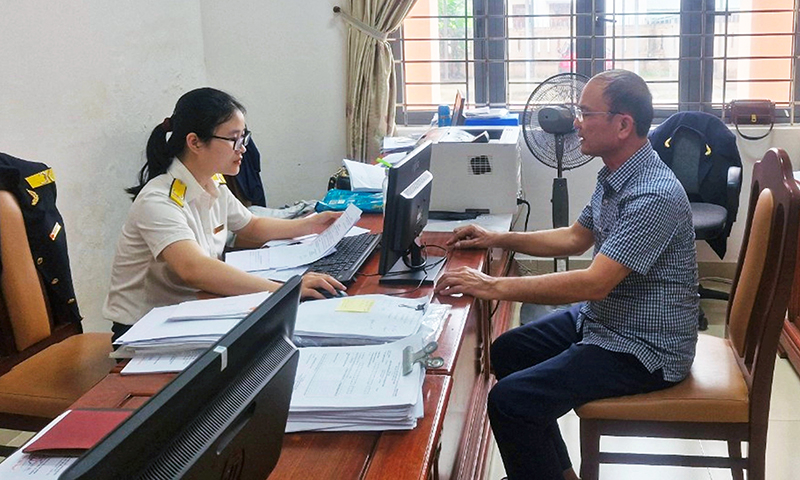 Cán bộ Chi cục Thuế huyện Bố Trạch tuyên truyền, hướng dẫn người nộp thuế thực hiện chuẩn hóa mã số thuế cá nhân.