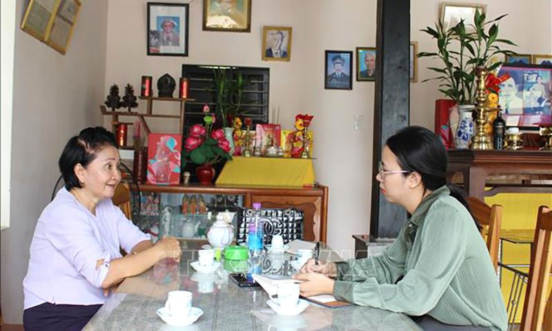 Phóng viên TTXVN trò chuyện với bà Nguyễn Thị Ngọc Bích, em gái liệt sĩ Nguyễn Thị Ngọc Oanh về sự kiện gia đình bà may 2 lá cờ giải phóng trước những năm 1975. Ảnh: Phan Sáu/TTXVN