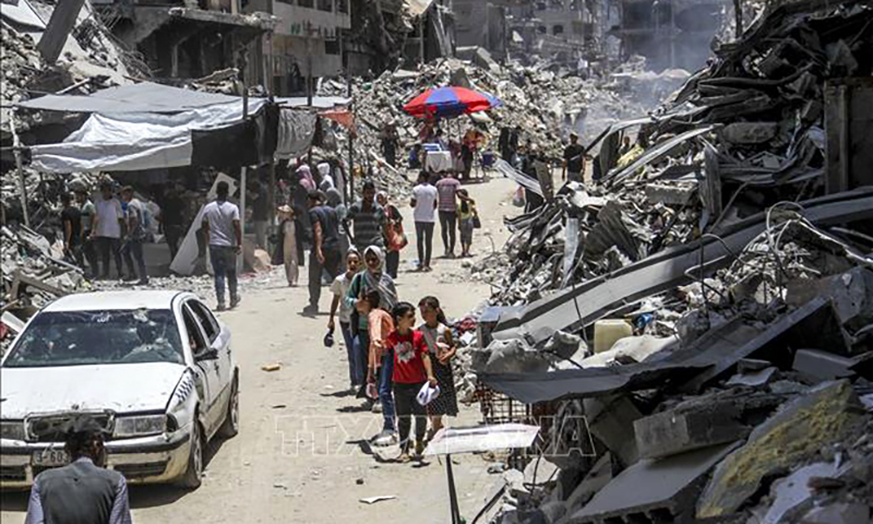 Người dân Palestine di chuyển dưới trời nắng nóng tại khu chợ trong trại tị nạn Jabalia, Dải Gaza, ngày 20/6/2024. Ảnh: THX/TTXVN