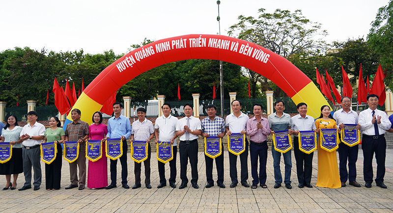 Lãnh đạo huyện Quảng Ninh tặng cờ lưu niệm cho các đơn vị tham gia gian hàng triển lãm thành tựu phát triển kinh tế-xã hội huyện năm 2024.