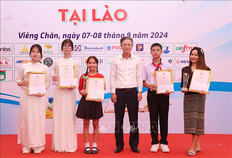 Đại biện lâm thời Đại sứ quán Việt Nam tại Lào Phan Minh Chiến trao phần thưởng cho các thí sinh đạt giải lễ Tôn vinh tiếng Việt tại Lào năm 2024. Ảnh: Xuân Tú/PV TTXVN tại Lào