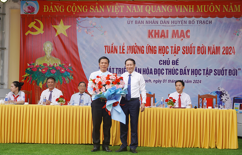 Đại diện lãnh đạo Ban Chỉ đạo Xây dựng xã hội học tập tỉnh tặng hoa chúc mừng Trường tiểu học và THCS Nam Trạch (huyện Bố Trạch).