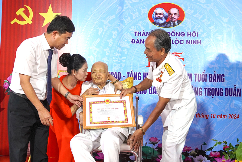 Đại diện Thường trực Thành ủy Đồng Hới gắn Huy hiệu 80 năm tuổi Đảng, trao chứng nhận cho đồng chí đồng chí Hoàng Trọng Duẫn.
