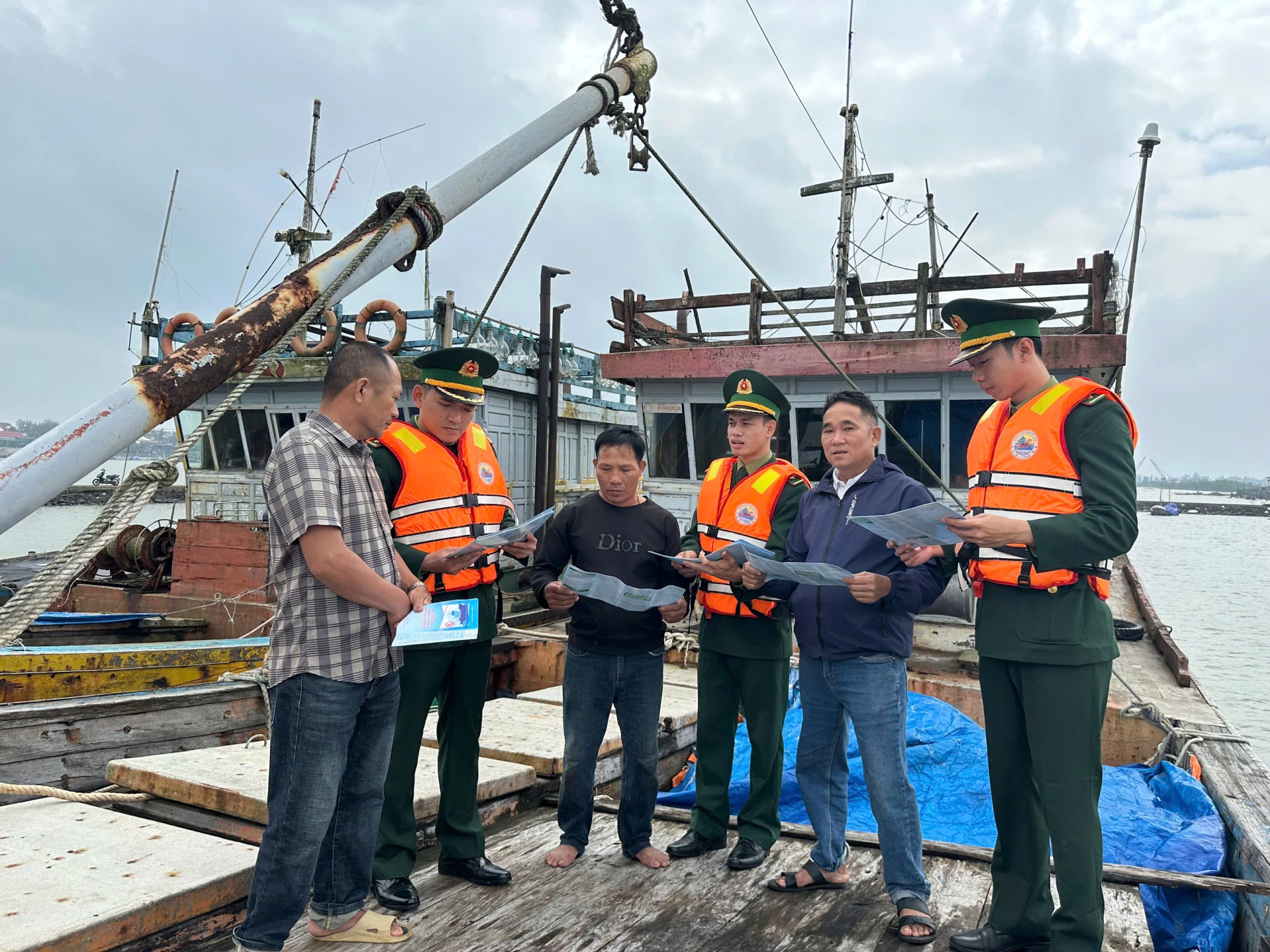 Cán bộ, chiến sĩ Đồn Biên phòng Cửa Tùng phát tờ rơi và tuyên truyền các quy định về chống khai thác IUU trực tiếp cho ngư dân - Ảnh: K.S