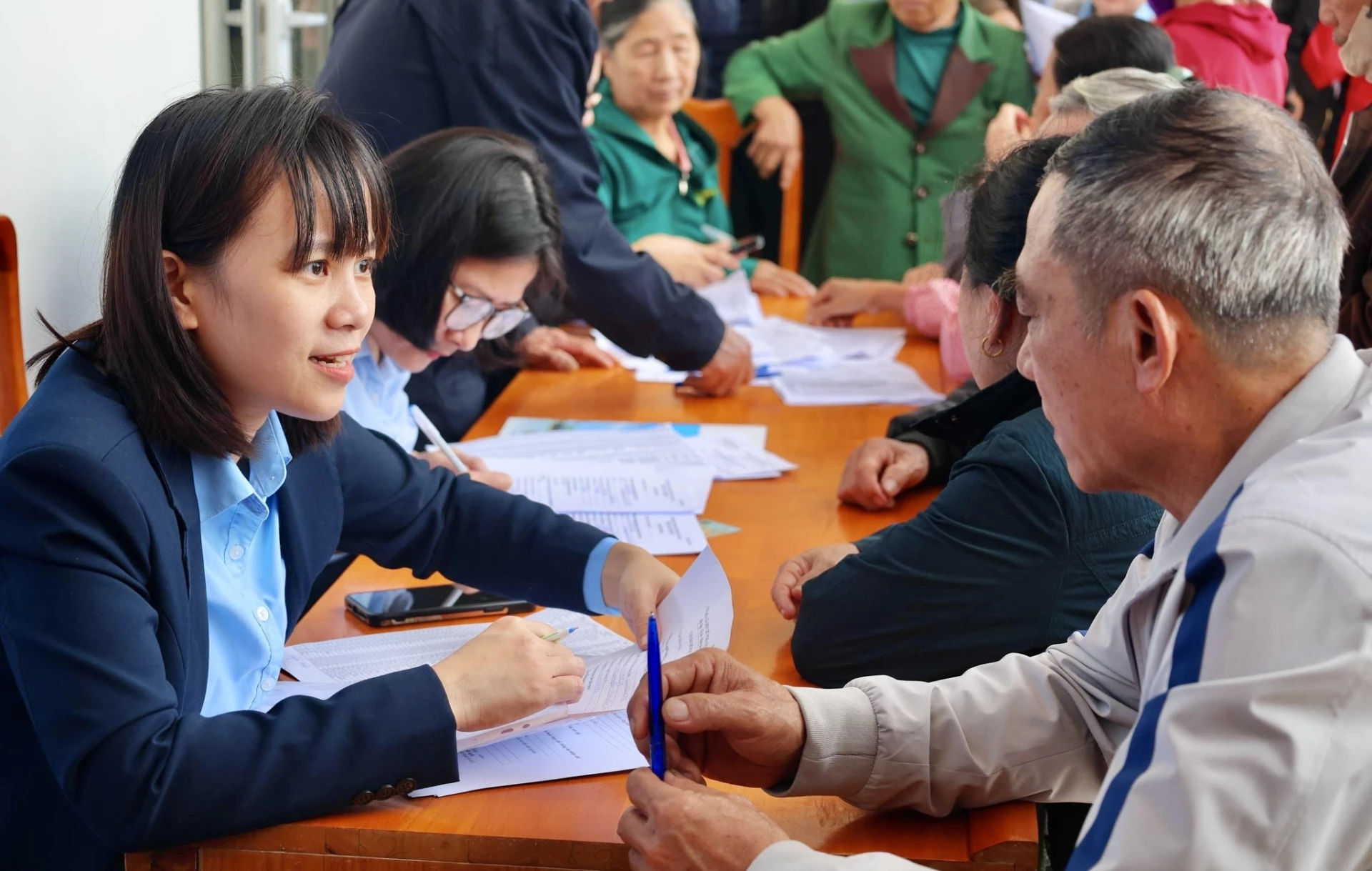 Cán bộ Bảo hiểm xã hội tỉnh hướng dẫn người dân chuyển đổi hình thức chi trả lương hưu không dùng tiền mặt - Ảnh: T.A