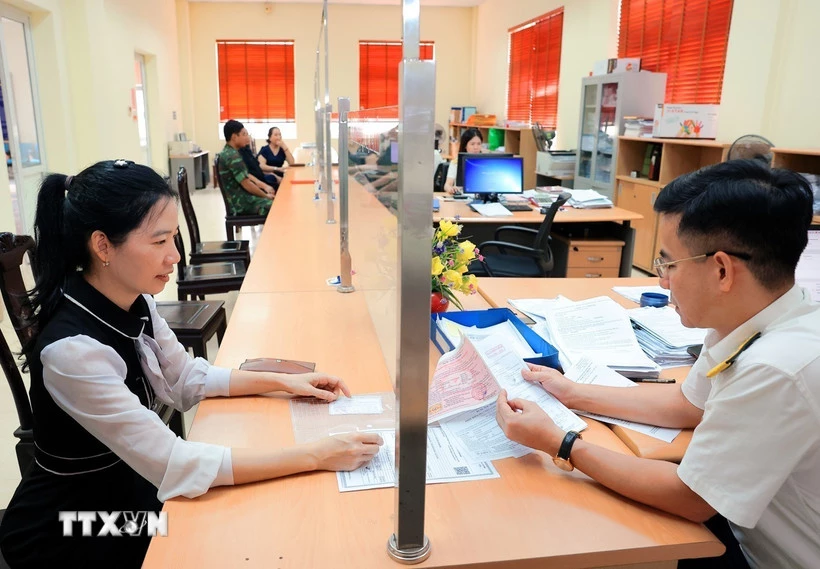 Hướng dẫn người dân làm thủ tục nộp thuế trước bạ. (Ảnh: Phạm Hậu/TTXVN)