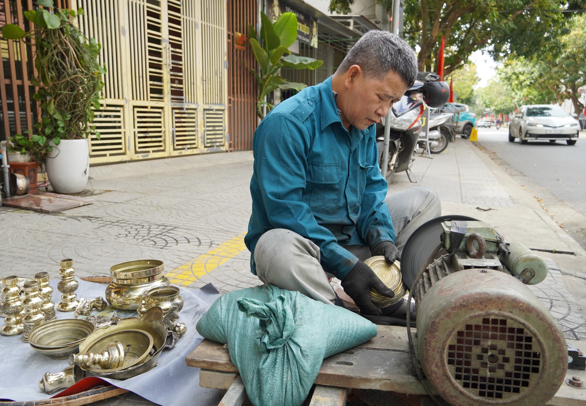 Ông Phạm Xuân Hoài miệt mài bên máy mô tơ đánh lư đồng những ngày giáp Tết -  Ảnh: C.N

