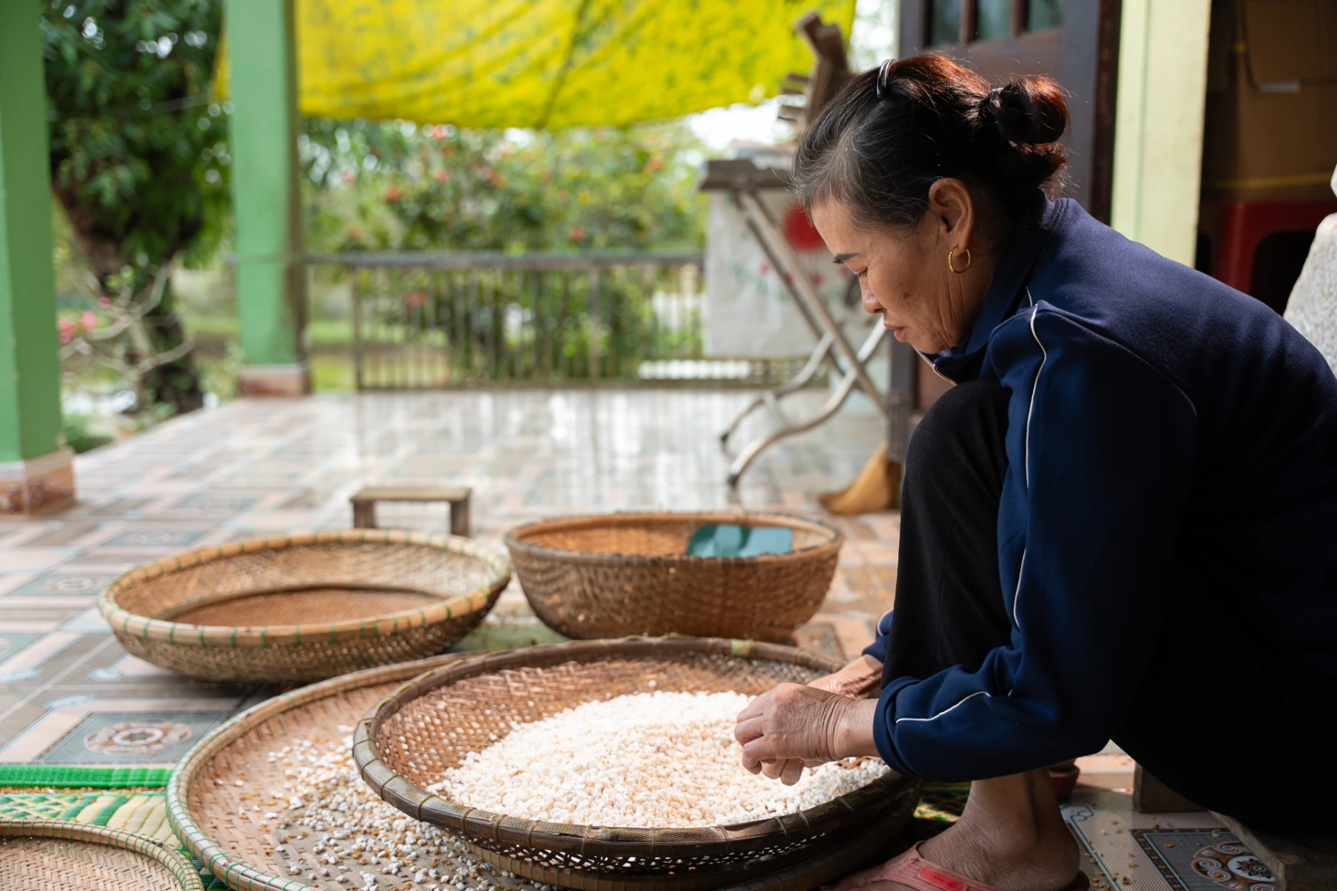 Bà Tạ Thị Thanh Trà tỉ mỉ với công đoạn sàng sảy nếp rang-Ảnh: L.N.T