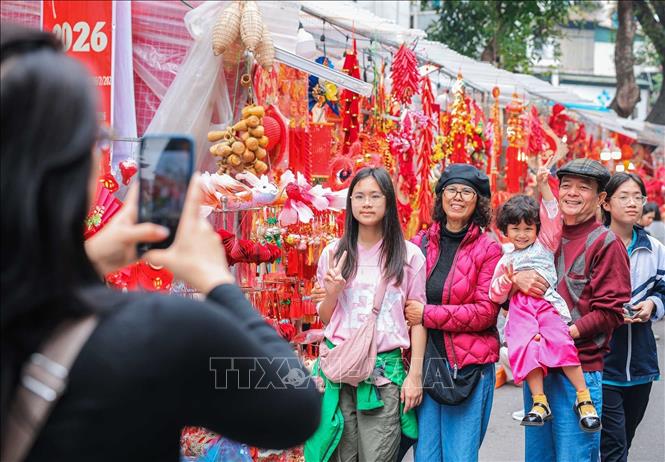Người dân lưu giữ kỷ niệm tại chợ hoa Hàng Lược (Hà Nội) những ngày cận Tết. Ảnh: Hoàng Hiếu/TTXVN