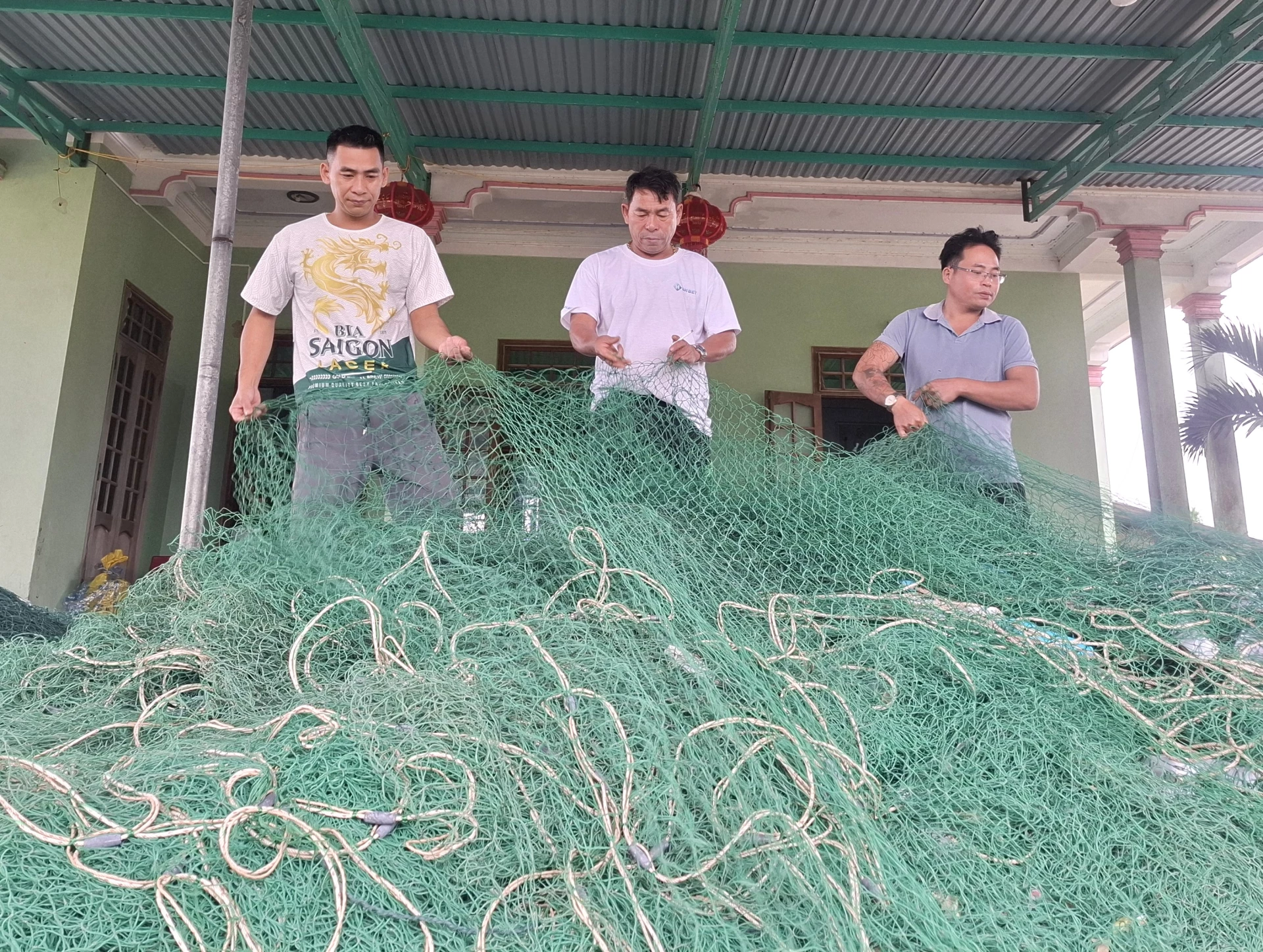 Ngư dân Võ Minh Toàn (ở giữa) chuẩn bị vàng lưới rê bùng nhùng để ra khơi, bám biển - Ảnh: S.H