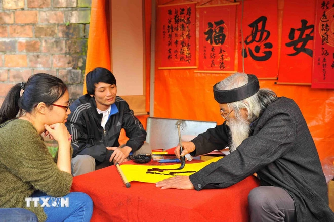 Các bạn trẻ mua chữ đầu năm lấy may. (Ảnh: Minh Đức/TTXVN)