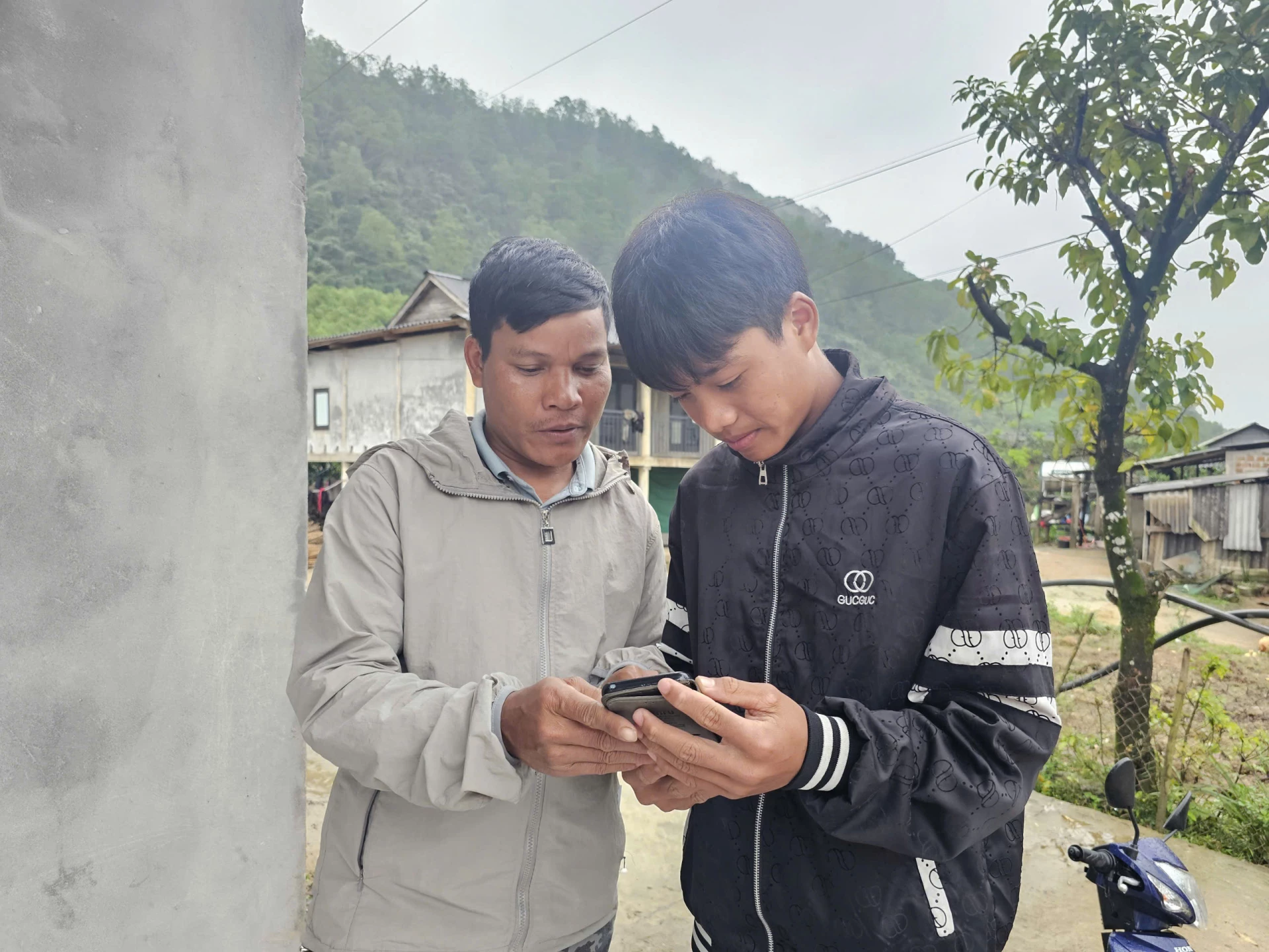 Trưởng thôn Đồng Đờng Hồ Văn Cu (bên trái) hướng dẫn người dân trong thôn ứng dụng các phần mềm trên smartphone - Ảnh: T.P