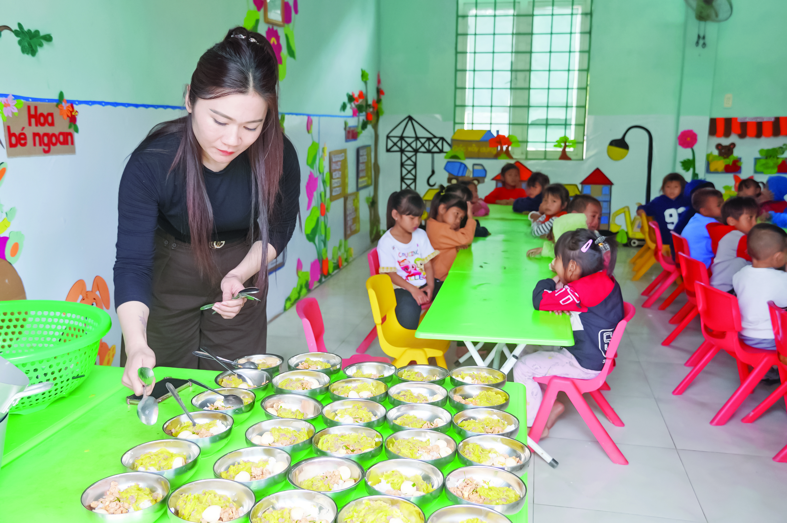 Cô giáo chuẩn bị bữa trưa cho các em học sinh người Mày tại điểm Trường mầm non bản Lòm - Ảnh: X.P