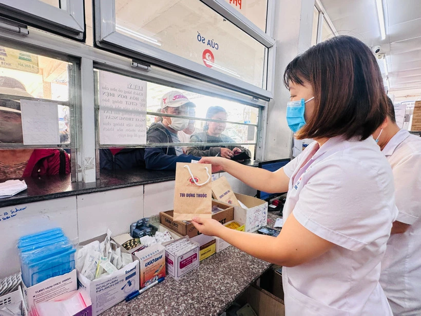 Nhân viên y tế cấp phát thuốc bảo hiểm y tế cho người bệnh. (Ảnh: T.G/Vietnam+)