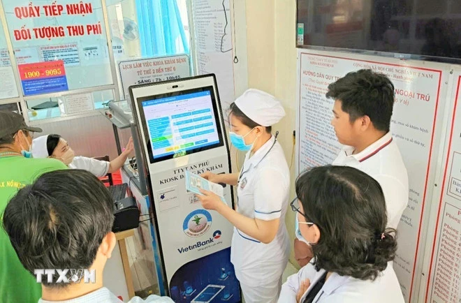 Cán bộ, nhân viên Trung tâm y tế An Phú, An Giang, hướng dẫn người dân đăng ký khám chữa bệnh bằng kiốt thông minh. (Ảnh: Công Mạo/TTXVN)
