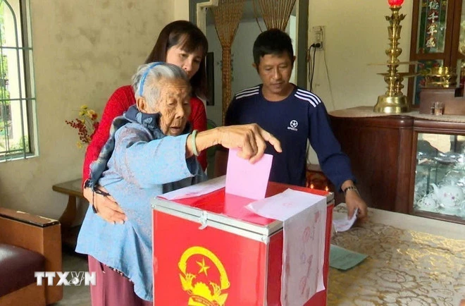 Lực lượng làm nhiệm vụ bầu cử đưa hòm phiếu phụ đến tận nhà để cử tri Nguyễn Thị Nhiễu, 90 tuổi trú xã Cam Lâm bỏ phiếu bầu cử Đại biểu Quốc hội khóa XVI và Đại biểu Hội đồng nhân dân các cấp nhiệm kỳ 2026-2031. (Ảnh: TTXVN phát)