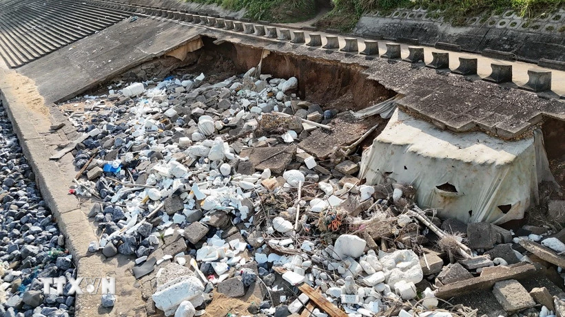Đoạn kè ven biển dài khoảng 60m bị sóng biển khoét sâu vào trong, lộ ra xi măng, cốt thép, đất... (Ảnh: Thanh Thủy/TTXVN)