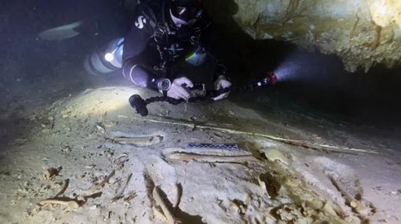 Nhà khảo cổ học Octavio del Río chụp ảnh một bộ xương người tiền sử được phát hiện bên trong hệ thống hang động ngập nước ở Actun, gần Tulum, Mexico. (Nguồn: AP)